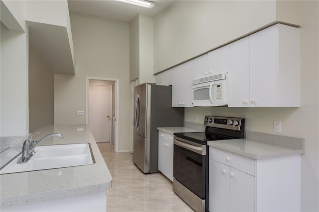 kitchen featuring a sink, light countertops, white cabinets, a high ceiling, and stainless steel appliances