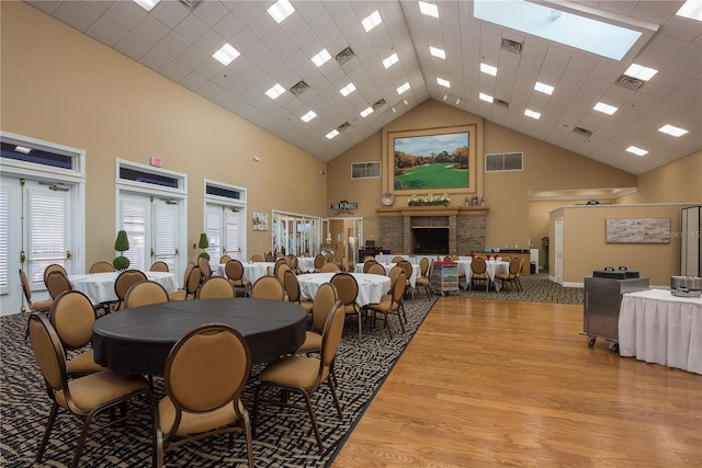 dining area with high vaulted ceiling, light wood-style flooring, and visible vents