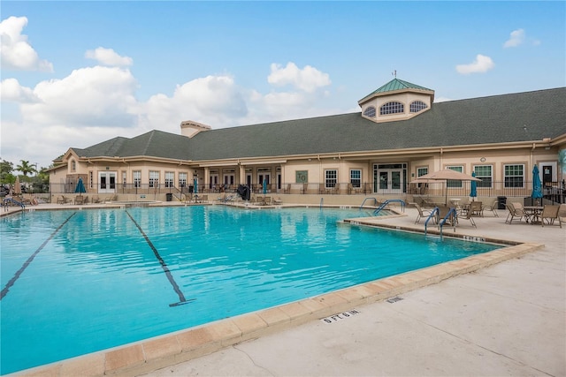 community pool featuring french doors, fence, and a patio area