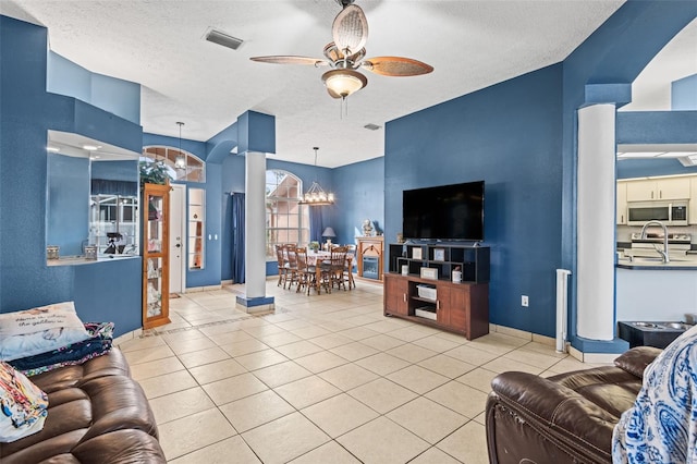 12040 Penzance Ln, New Port Richey, FL 34654 - tiled living room with a chandelier, a textured ceiling, ceiling fan, decorative columns, and baseboards