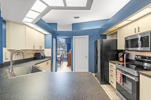 12040 Penzance Ln, New Port Richey, FL 34654 - kitchen with stainless steel appliances, a sink, decorative backsplash, dark countertops, and cream cabinets