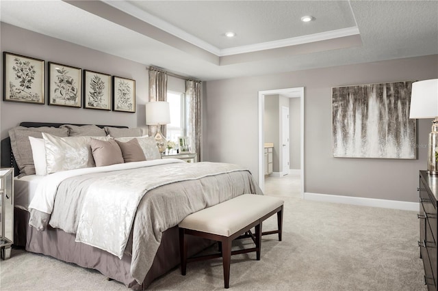 bedroom featuring ornamental molding, light carpet, baseboards, ensuite bathroom, and a tray ceiling