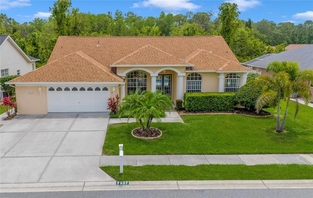 7827 Starfire Way, New Port Richey, FL 34654 - view of front of property featuring stucco siding, a garage, concrete driveway, a front lawn, and roof with shingles