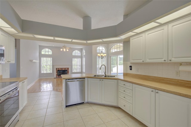 7827 Starfire Way, New Port Richey, FL 34654 - kitchen with appliances with stainless steel finishes, a sink, a brick fireplace, ceiling fan, and a peninsula