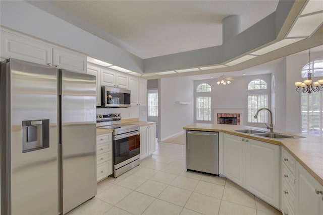 7827 Starfire Way, New Port Richey, FL 34654 - kitchen featuring appliances with stainless steel finishes, a brick fireplace, a sink, white cabinetry, and light tile patterned floors