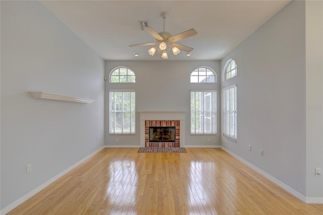 7827 Starfire Way, New Port Richey, FL 34654 - unfurnished living room featuring plenty of natural light, light wood-type flooring, a ceiling fan, and a fireplace