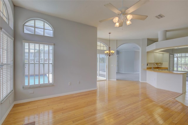 7827 Starfire Way, New Port Richey, FL 34654 - unfurnished living room featuring a chandelier, light wood-style flooring, a sink, and a ceiling fan