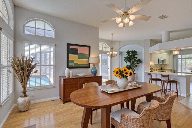 7827 Starfire Way, New Port Richey, FL 34654 - dining area with light wood-style flooring, a ceiling fan, baseboards, and a chandelier