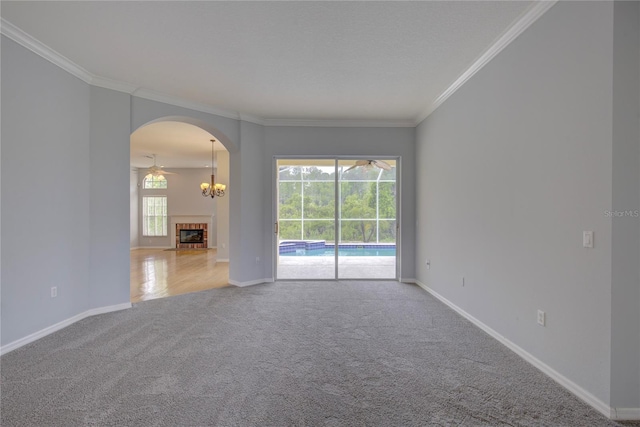 7827 Starfire Way, New Port Richey, FL 34654 - carpeted spare room featuring crown molding, baseboards, arched walkways, a ceiling fan, and a tile fireplace