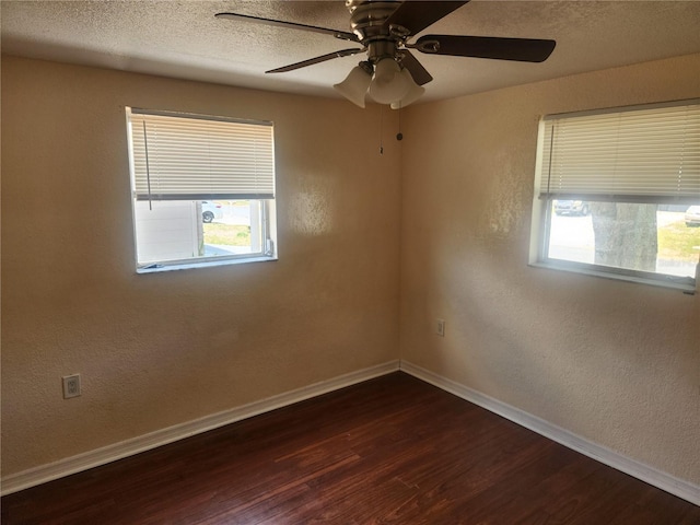 spare room featuring plenty of natural light, a ceiling fan, dark wood-style flooring, and baseboards