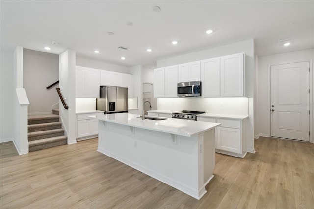 5240 Luisa Ct, Saint Cloud, FL 34771 - kitchen with appliances with stainless steel finishes, a sink, an island with sink, white cabinets, and light wood-type flooring