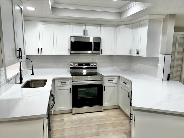 kitchen with crown molding, white cabinetry, appliances with stainless steel finishes, and a sink