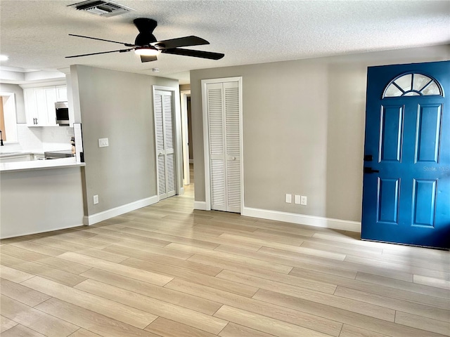 foyer featuring visible vents, a textured ceiling, ceiling fan, and light wood-type flooring
