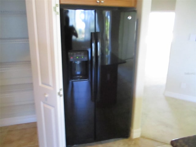 interior details featuring baseboards and black fridge