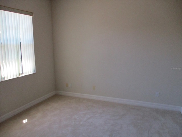 spare room with a healthy amount of sunlight, baseboards, and light carpet