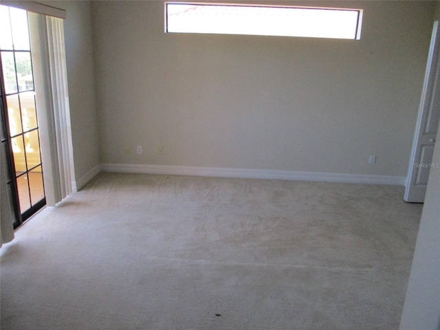 unfurnished room featuring a healthy amount of sunlight, baseboards, and light colored carpet