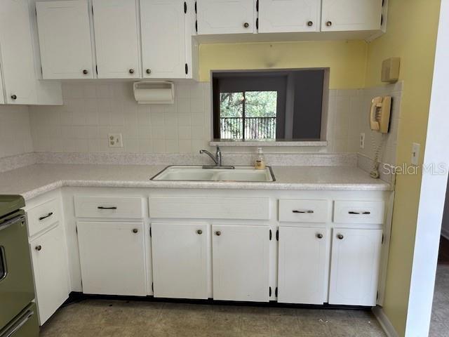 840 Virginia St Unit 202, Dunedin, FL 34698 - kitchen featuring a sink, light countertops, stove, and white cabinetry
