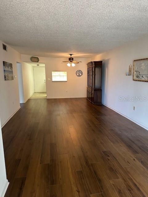 840 Virginia St Unit 202, Dunedin, FL 34698 - unfurnished living room featuring visible vents, dark wood-style flooring, baseboards, ceiling fan, and a textured ceiling