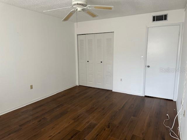 840 Virginia St Unit 202, Dunedin, FL 34698 - unfurnished bedroom featuring visible vents, a textured ceiling, dark wood finished floors, and a closet