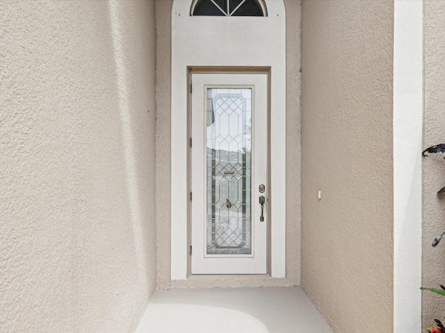 doorway to property featuring stucco siding