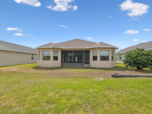 rear view of property featuring a sunroom, stucco siding, and a lawn