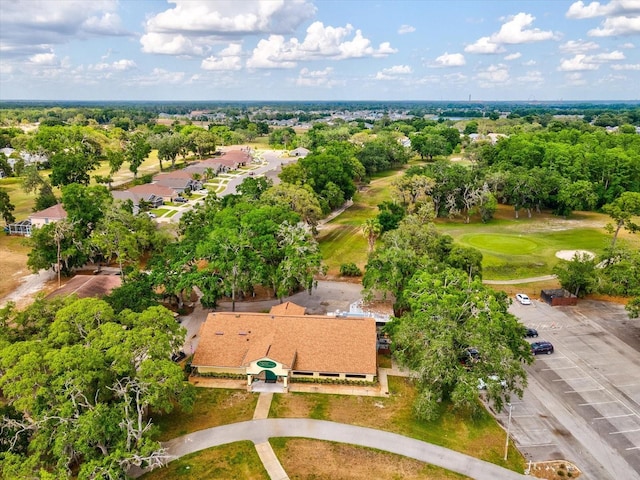 aerial perspective of suburban area featuring a golf course and a tree filled landscape