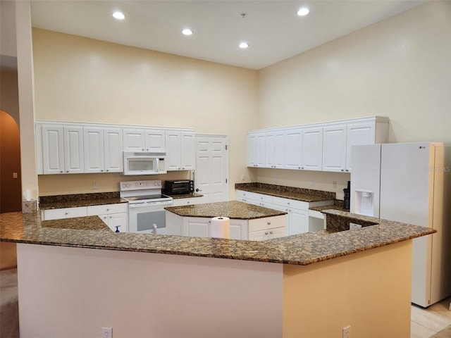 21008 Sunpoint Way Unit 204, Lutz, FL 33558 - kitchen featuring a towering ceiling, a center island, arched walkways, dark stone counters, and white appliances