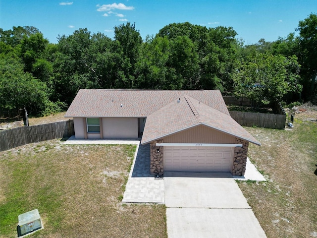 2660 Orangewood Ct, Palm Harbor, FL 34684 - view of front of home featuring fence, an attached garage, stone siding, a front yard, and driveway