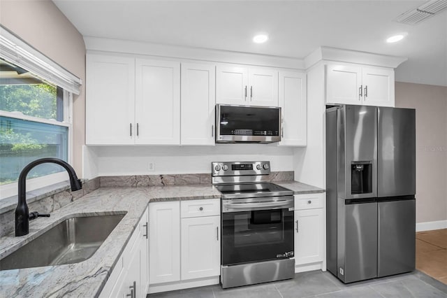 2660 Orangewood Ct, Palm Harbor, FL 34684 - kitchen with visible vents, light stone countertops, a sink, white cabinets, and stainless steel appliances