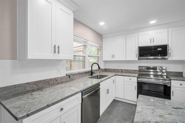 2660 Orangewood Ct, Palm Harbor, FL 34684 - kitchen featuring light stone countertops, dark tile patterned floors, white cabinets, a sink, and stainless steel appliances