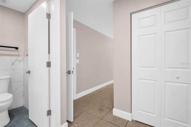 2660 Orangewood Ct, Palm Harbor, FL 34684 - bathroom with tile patterned flooring, baseboards, toilet, and tile walls