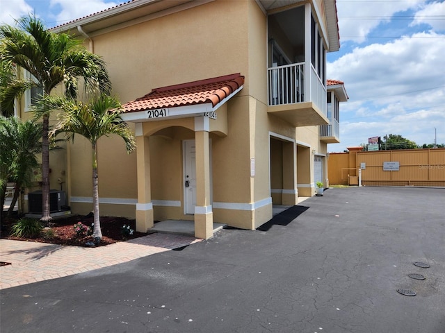 exterior space featuring fence, stucco siding, a tile roof, and a balcony