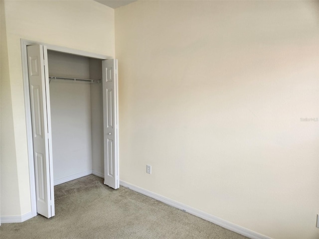 unfurnished bedroom featuring carpet flooring, baseboards, and a closet