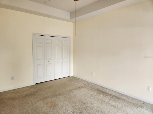 unfurnished bedroom featuring baseboards, carpet, and a closet