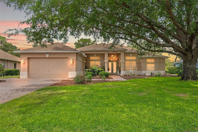 view of front of house with a garage, a front lawn, stucco siding, french doors, and driveway