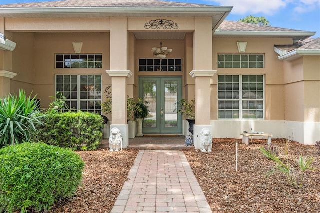 property entrance featuring french doors, a shingled roof, and stucco siding