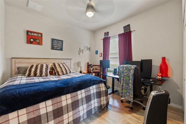 bedroom with visible vents, baseboards, ceiling fan, and wood finished floors