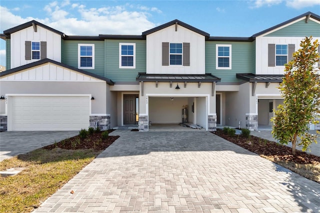 townhome / multi-family property featuring decorative driveway, a standing seam roof, metal roof, and stone siding