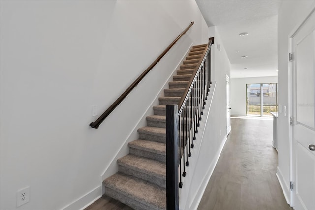 stairway featuring baseboards and wood finished floors