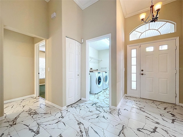 entryway with separate washer and dryer, light marble finish floors, a towering ceiling, baseboards, and a chandelier