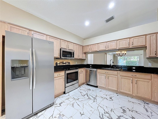 kitchen with appliances with stainless steel finishes, light brown cabinets, a sink, dark countertops, and recessed lighting