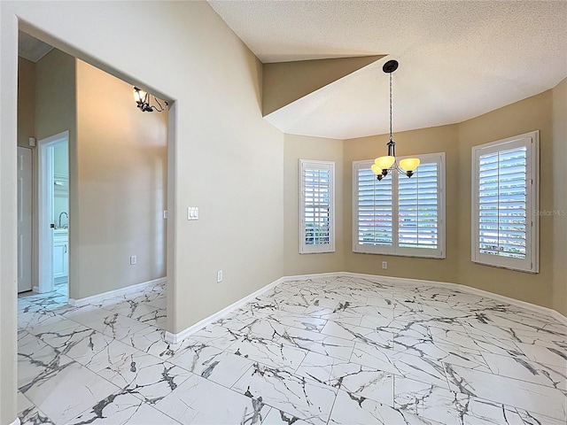 empty room featuring a chandelier, light marble finish flooring, baseboards, and a textured ceiling