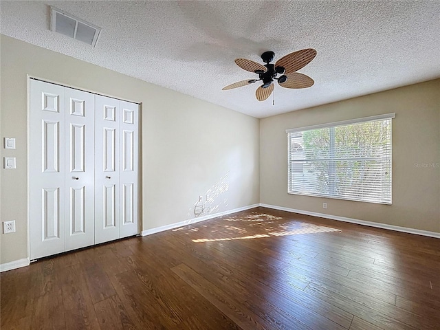 unfurnished bedroom with hardwood / wood-style floors, a textured ceiling, baseboards, a closet, and a ceiling fan
