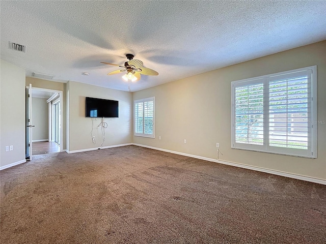 unfurnished room featuring a ceiling fan, a textured ceiling, dark colored carpet, and baseboards