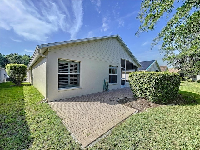 back of property with a lawn, a patio, and stucco siding