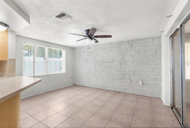 unfurnished room with visible vents, a textured ceiling, ceiling fan, and light tile patterned flooring