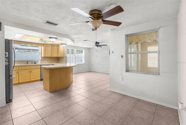 kitchen featuring light brown cabinetry, ceiling fan, appliances with stainless steel finishes, light countertops, and visible vents