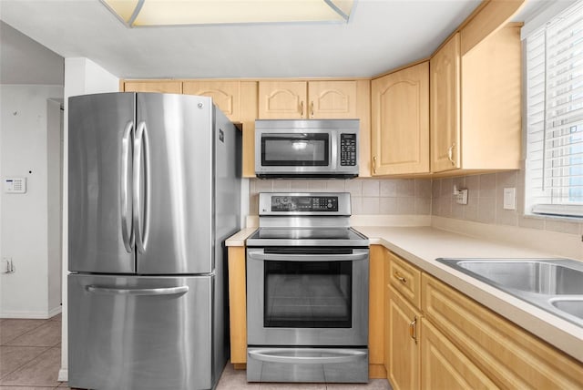 kitchen with light countertops, backsplash, light brown cabinets, and stainless steel appliances