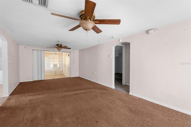 carpeted empty room with arched walkways, baseboards, a ceiling fan, and visible vents