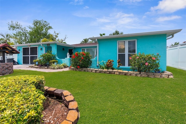 view of front of house with stucco siding, fence, and a front yard